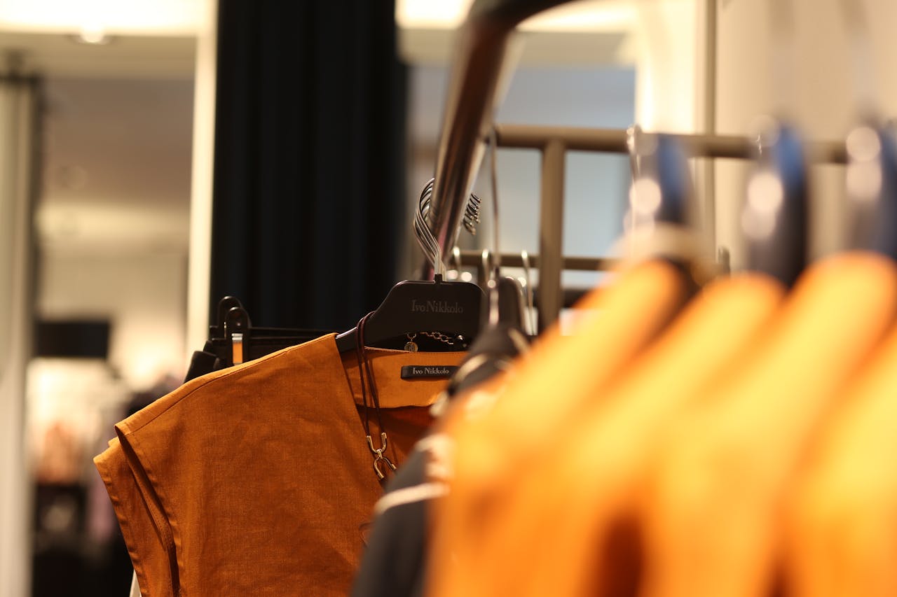 about-01 Close-up of clothing hanging in a well-lit fashion boutique, showcasing trendy styles.