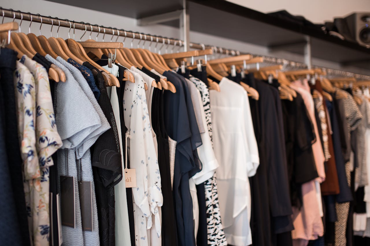 our-services-2 Vibrant clothing display on wooden hangers in a modern boutique setting.